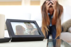 Framed photo with shattered glass in foreground, woman with head in hands behind.