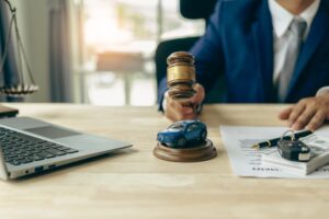 Lawyer with a gavel and a toy car on a desk with documents.