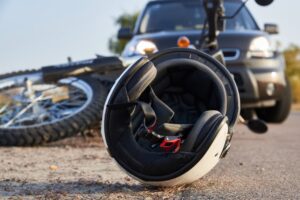 Image depicting a scene of road accidents with a car, helmet, and motorcycle on the road.