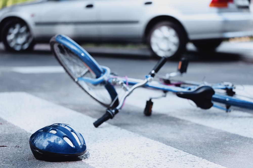 Bicycle and helmet on road after collision with car, signaling accident.