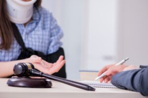 An injured person with a neck brace and arm sling consulting with a lawyer at a desk.