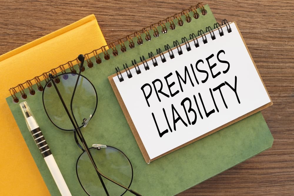 A notepad with "Premises Liability" text, glasses, and pen on a wooden table.