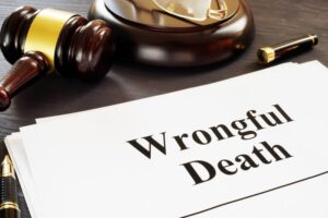 Documents labeled "Wrongful Death" on a desk, with a judge's gavel and a fountain pen, indicating legal proceedings.