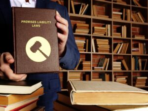 Person holding a book titled "Premises Liability Laws" in a library.