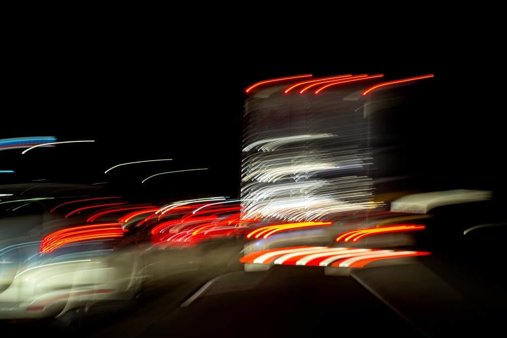 Blurred image of a truck at night, showing light trails and speed, emphasizing the danger of impaired driving on the road.