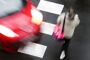 a red car about to hit a pedestrian on crosswalk