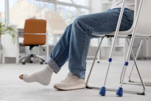 Injured young man after accident with crutches sitting in clinic