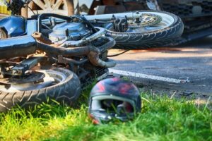 Motorcycle lying on grass after a collision, with helmet nearby