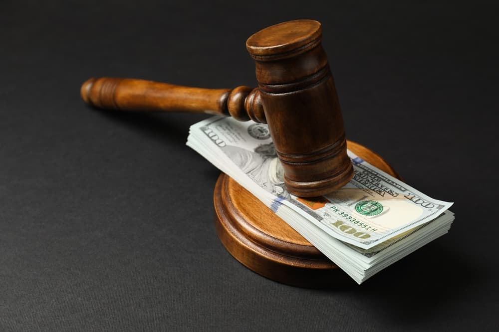 Law gavel with stack of dollars on black table