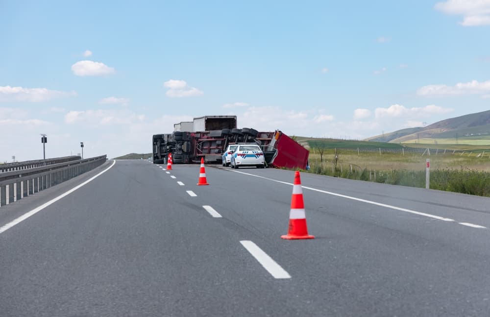 An overloaded and fast truck (TIR) overturned on an interurban road - Traffic police cars are at the scene of the accident investigating the incident